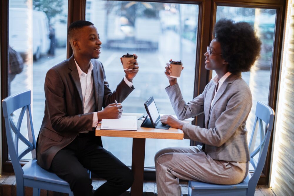 African partners drinking coffee during meeting at cafe