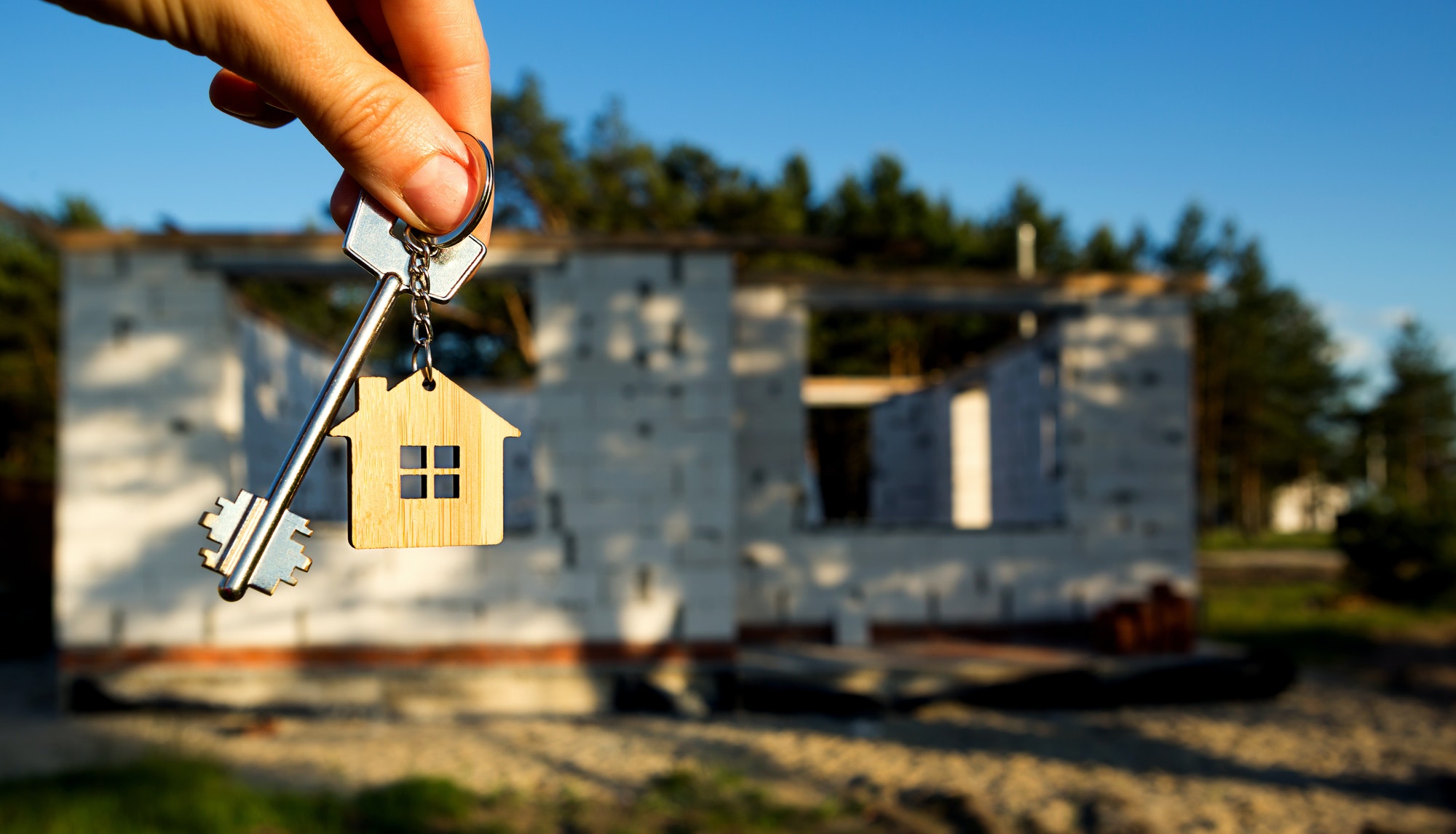 and with the key to the future house on the background of a construction site